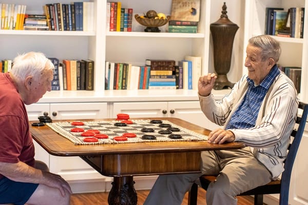 Two residents playing checkers in a common area