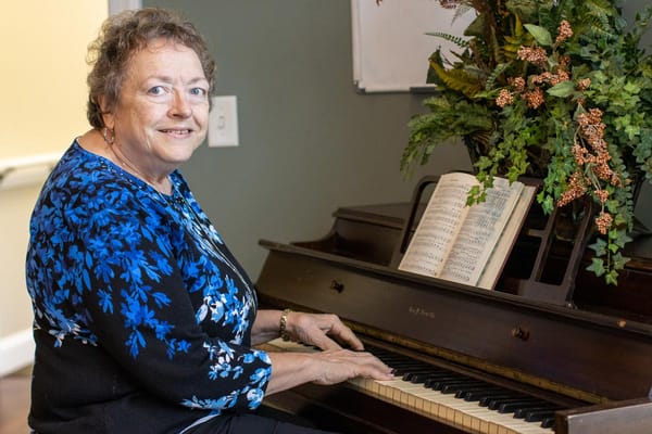 Resident playing piano in a warm common area