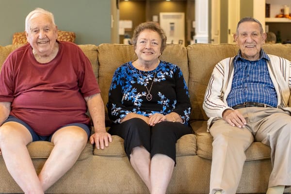 Residents smiling together on a couch in a common area