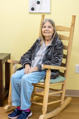 Resident relaxing in a rocking chair inside the facility