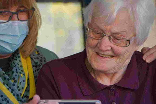 Resident and staff member engaged with a smartphone