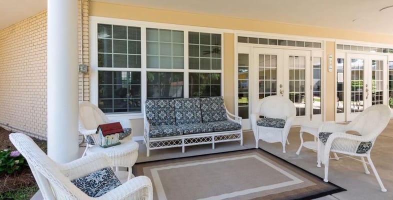 Seating area on a covered porch with white chairs