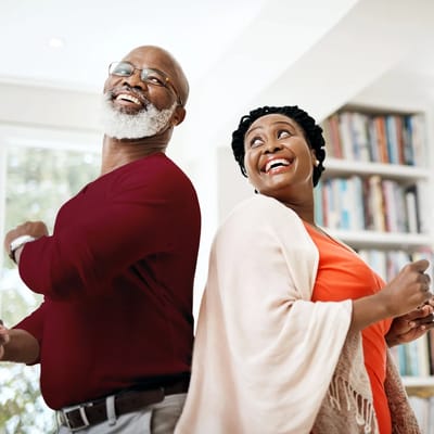 Two seniors dancing and smiling in a bright room