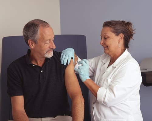 A healthcare professional administering a vaccine to a senior man.