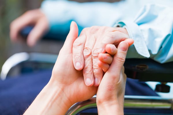 Hands of a caregiver and a senior holding each other