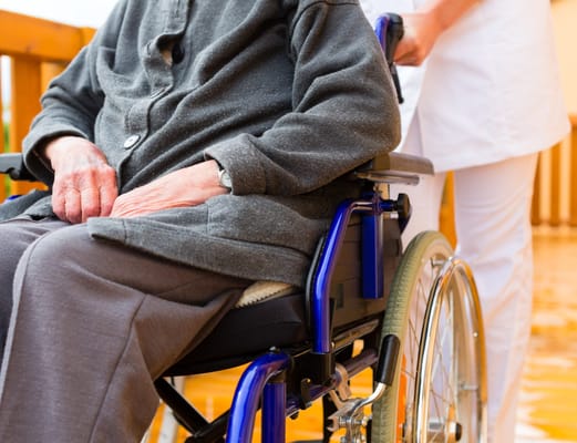 Close-up of a resident in a wheelchair with staff assistance