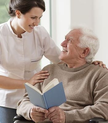 Caregiver interacting with a resident holding a book