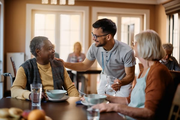Residents enjoying a meal with staff in a dining area