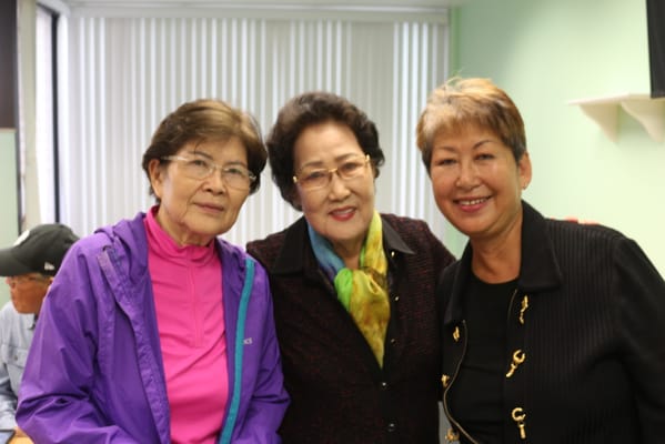 Three women smiling together in a common area