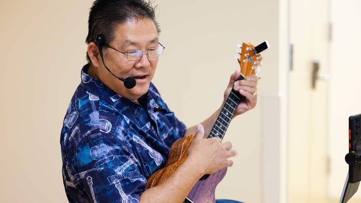 Resident enjoying a ukulele performance in a common area