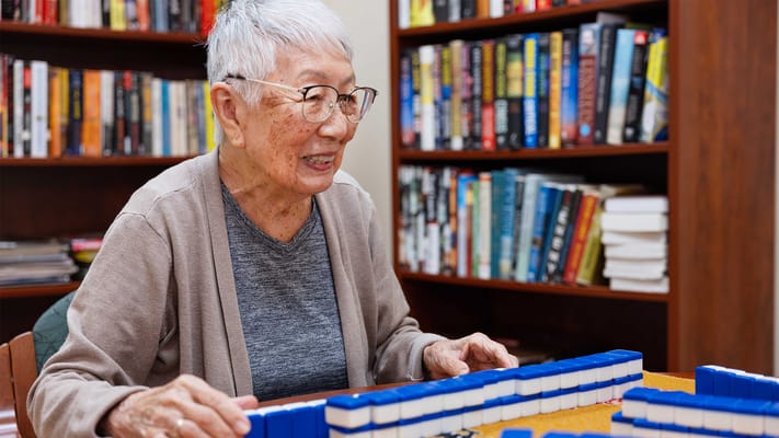Resident playing mahjong in a cozy library