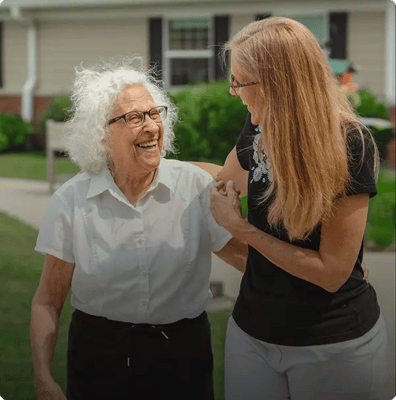 A resident and staff member joyfully interacting outdoors.