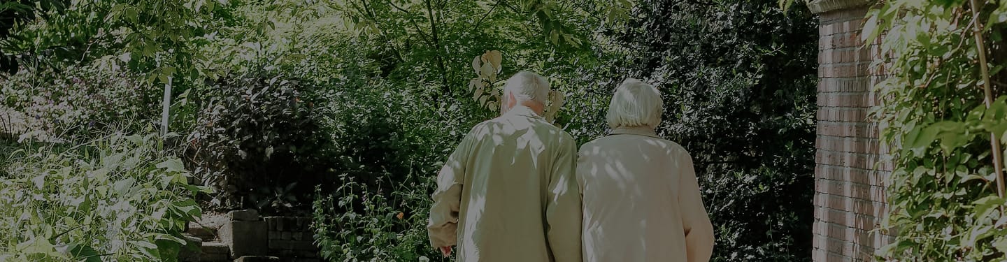 Two residents walking through a lush garden path