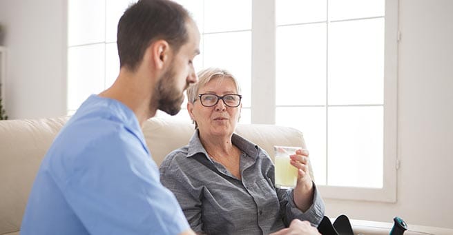 Resident enjoying a drink with staff in a cozy setting
