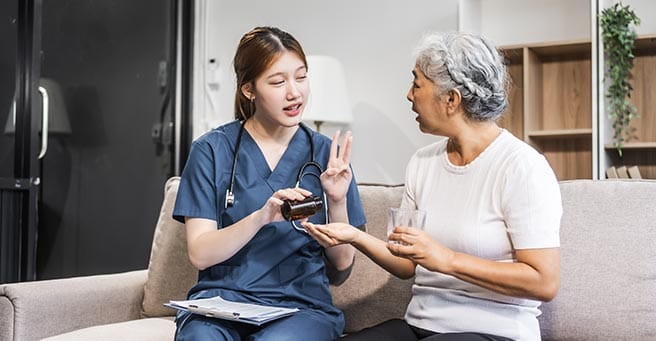Healthcare staff assisting an older resident in a cozy living room
