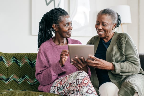 Two residents engaging with a tablet in a cozy living area