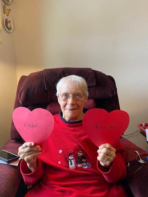 Resident holding heart cutouts in a cozy chair