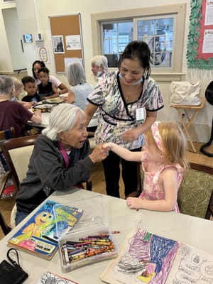Residents engaging with a staff member and a child during an activity