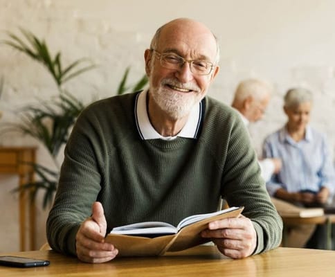 Smiling resident reading in a cozy activity room