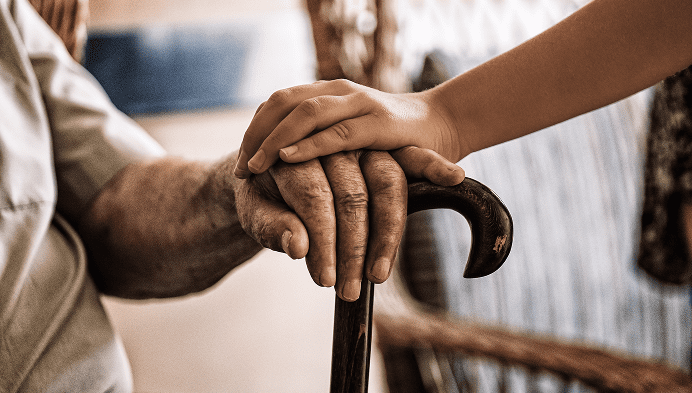 Close-up of a hand on a cane with a child's hand resting on top