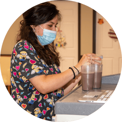 Staff member preparing drinks in a facility kitchen