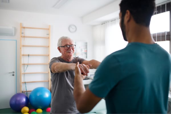 Therapist assisting senior man in a bright activity room