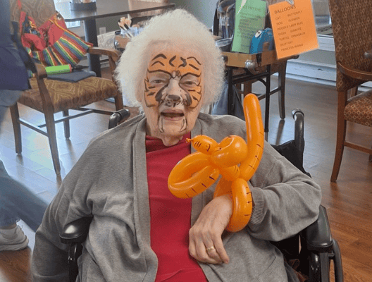 Resident with face paint and balloon in a social setting