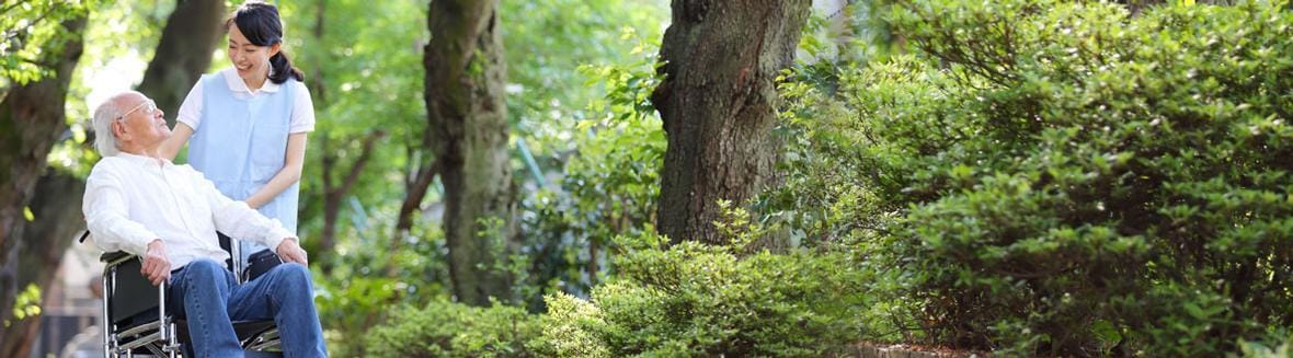 Healthcare staff assisting a resident in a garden