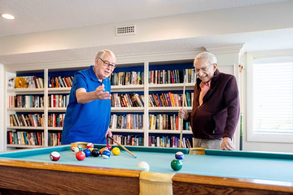 Two residents enjoying a game of billiards in a common area