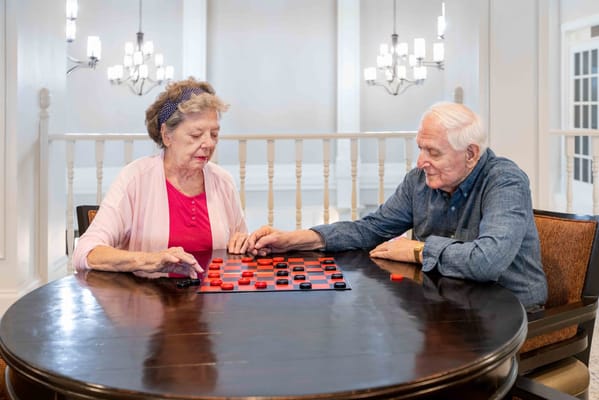 Two residents playing checkers in a common area