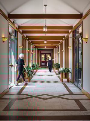 A well-lit hallway with residents and plants