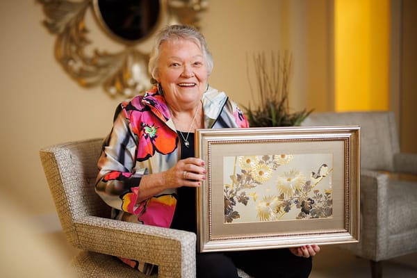 Resident smiling and holding a framed artwork