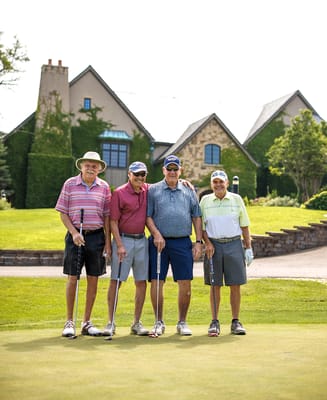 Four seniors playing golf in front of a facility