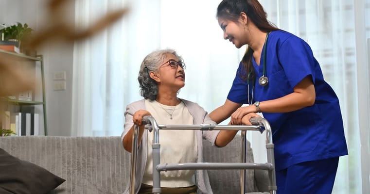 A caregiver assisting a resident with a walker in a living space