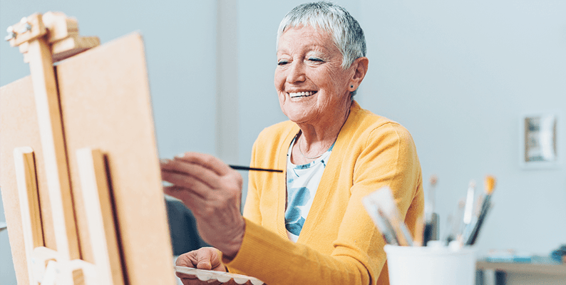 Senior woman painting in a bright activity room