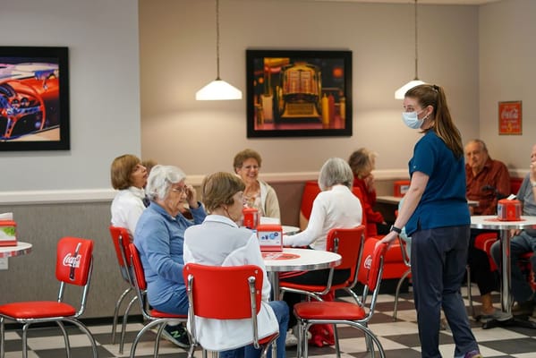 Residents enjoying a meal in the dining area with staff assistance