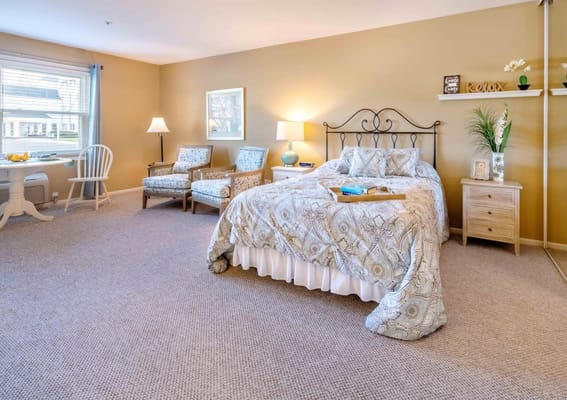 Brightly lit private resident room with bed and seating