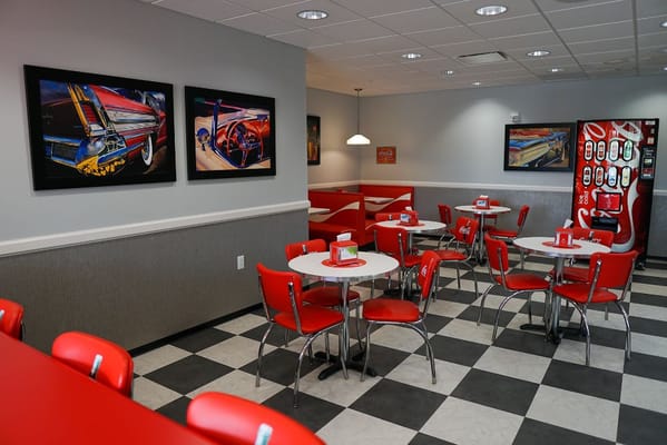 Dining area with red chairs and vintage car artwork