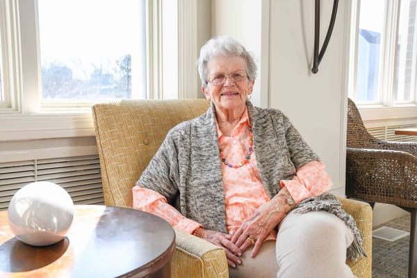 Senior resident smiling in a cozy lounge chair
