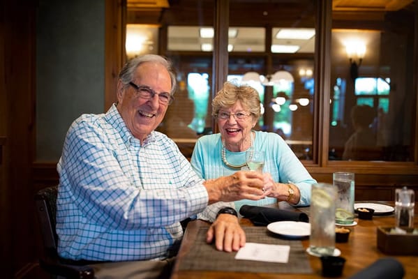Two residents enjoying drinks and smiling at a dining table