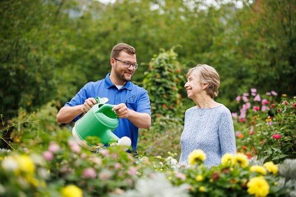 Care staff helping a resident in a vibrant garden