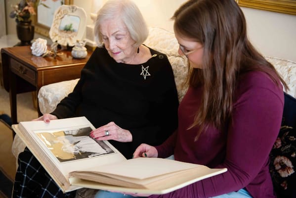 An elderly woman and a caregiver looking at a photo album together