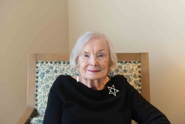 A senior resident smiling in a comfortable chair.