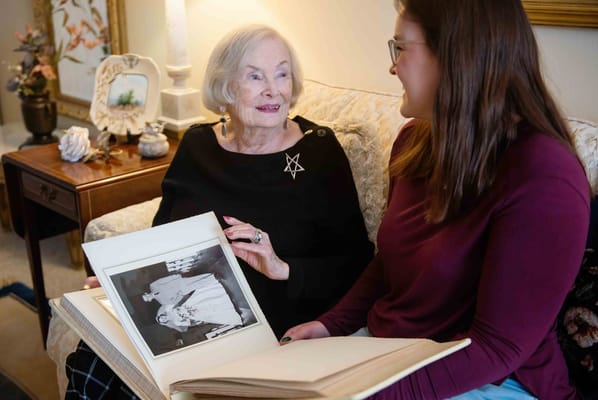 Elderly woman looking at a photo album with a caregiver