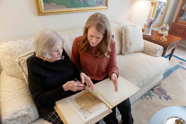 A resident and staff member looking at a scrapbook