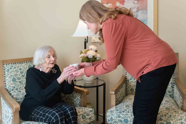 Staff assisting a resident in a cozy seating area