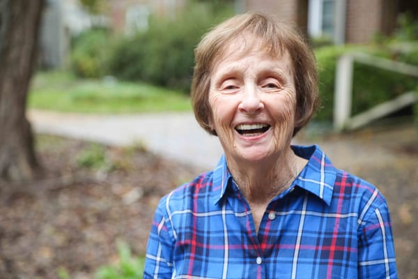 A smiling resident outside in a plaid shirt