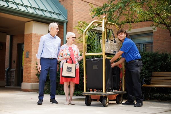 A resident and staff member with luggage at the entrance