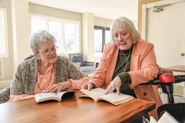 Two residents reading books together in a common area