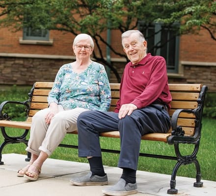 Two residents sitting on a bench in a garden area